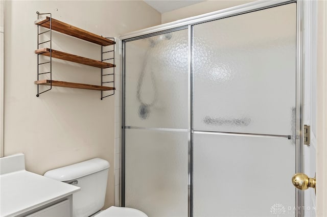 bathroom featuring toilet, vanity, and a shower with door