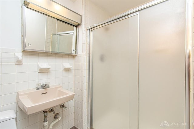 bathroom featuring toilet, tile walls, sink, and walk in shower