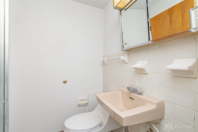 bathroom with toilet, tile walls, and sink