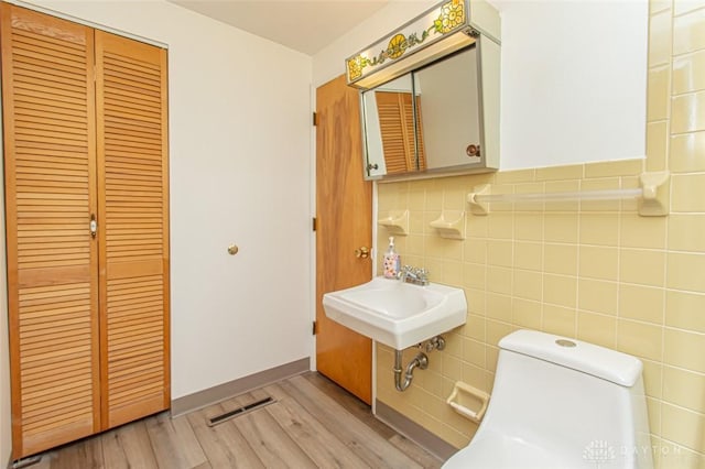 bathroom featuring toilet, tile walls, sink, and hardwood / wood-style floors