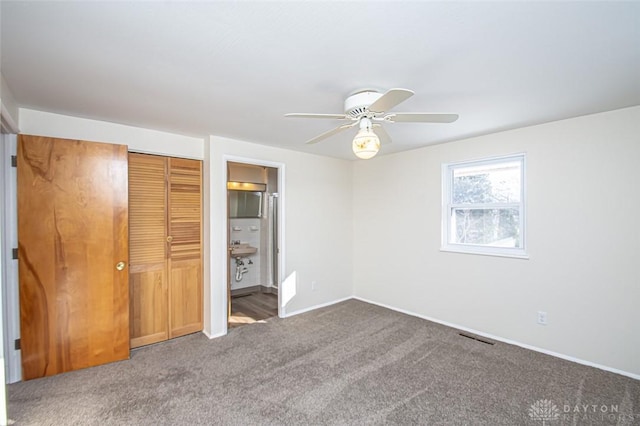 unfurnished bedroom with ceiling fan, a closet, ensuite bath, and carpet floors