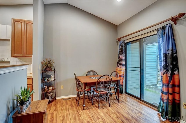 dining room featuring light wood-type flooring, a wealth of natural light, and lofted ceiling