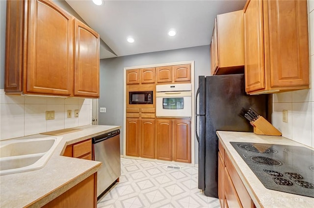 kitchen featuring sink, black appliances, and tasteful backsplash