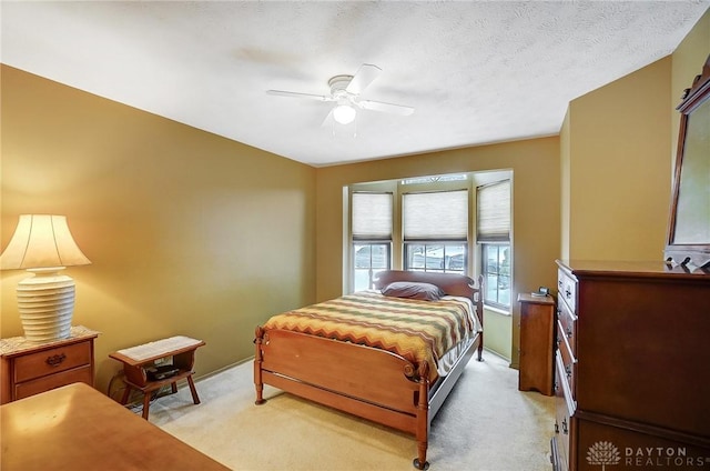 carpeted bedroom featuring ceiling fan and a textured ceiling