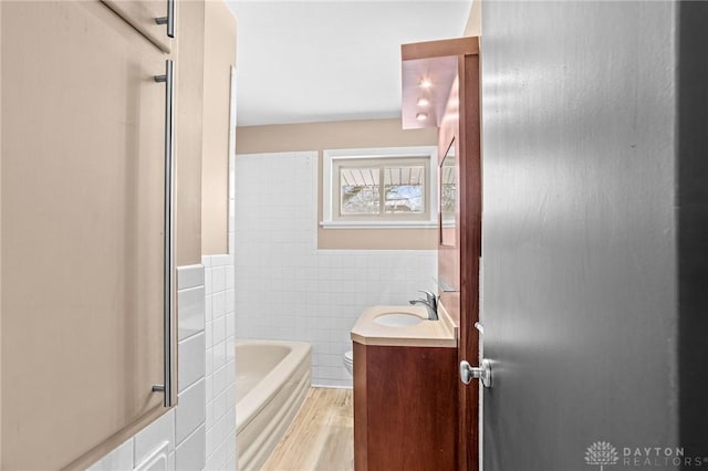 full bathroom with toilet, hardwood / wood-style flooring, tile walls, shower / bathtub combination, and vanity