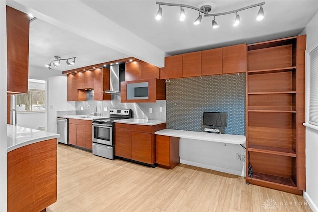 kitchen with light hardwood / wood-style floors, decorative backsplash, appliances with stainless steel finishes, and wall chimney range hood