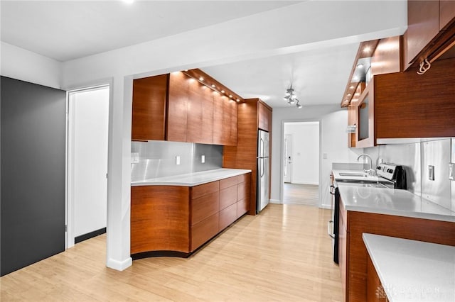 kitchen featuring decorative backsplash, sink, stainless steel appliances, and light hardwood / wood-style flooring