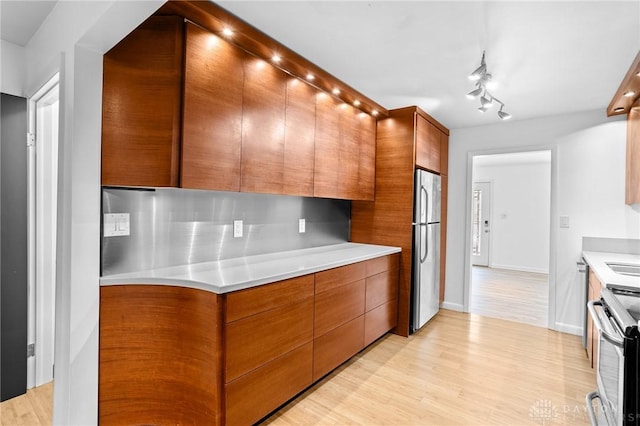 kitchen featuring appliances with stainless steel finishes, light hardwood / wood-style flooring, and tasteful backsplash