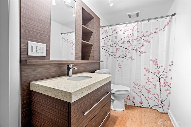 bathroom featuring wood-type flooring, toilet, vanity, and a shower with shower curtain