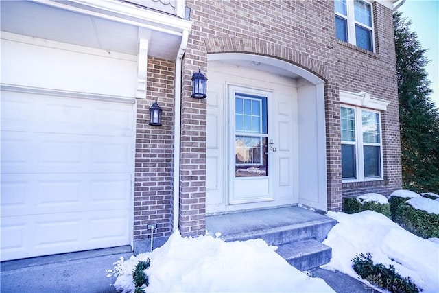 snow covered property entrance featuring a garage