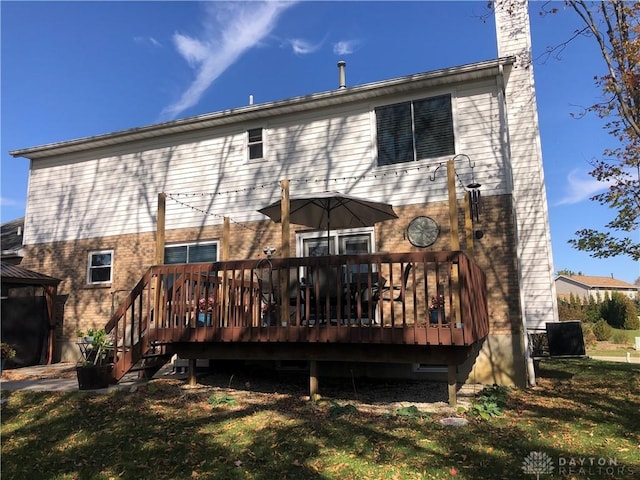 back of property with a yard and a wooden deck