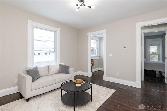 living room with dark wood-type flooring and a notable chandelier