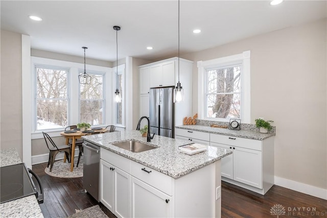 kitchen with stainless steel appliances, a kitchen island with sink, hanging light fixtures, white cabinets, and sink