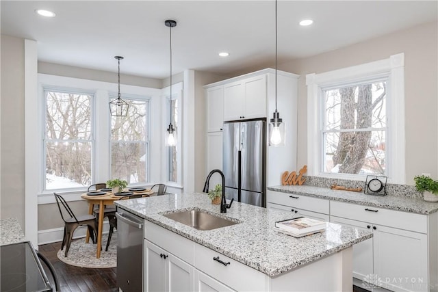 kitchen with stainless steel appliances, an island with sink, white cabinets, and sink