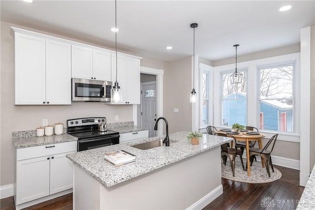 kitchen featuring white cabinetry, a center island with sink, stainless steel appliances, pendant lighting, and sink