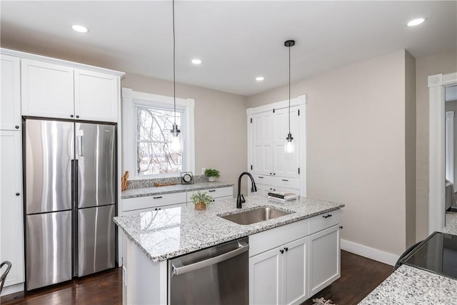 kitchen featuring pendant lighting, sink, white cabinetry, light stone countertops, and appliances with stainless steel finishes