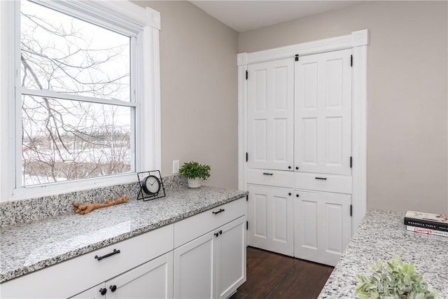 interior space featuring light stone countertops, white cabinets, and dark hardwood / wood-style flooring