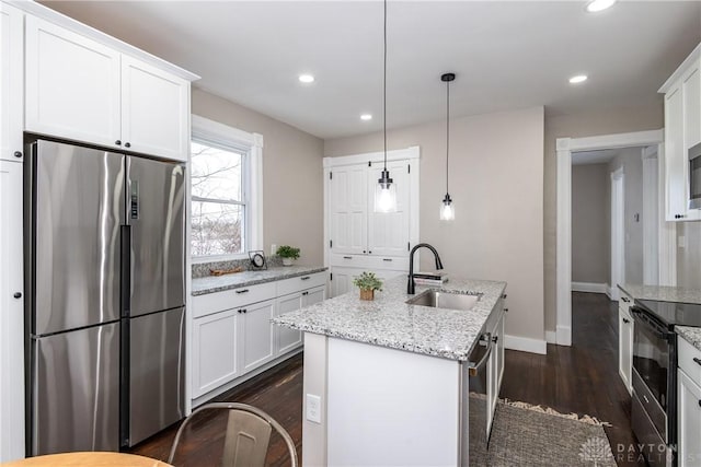 kitchen featuring a center island with sink, stainless steel fridge, hanging light fixtures, white cabinets, and sink