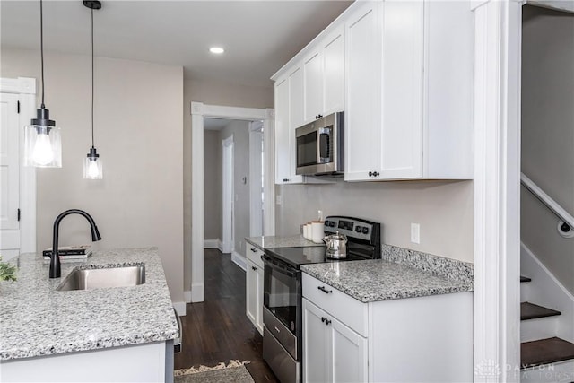 kitchen featuring decorative light fixtures, white cabinets, appliances with stainless steel finishes, and sink