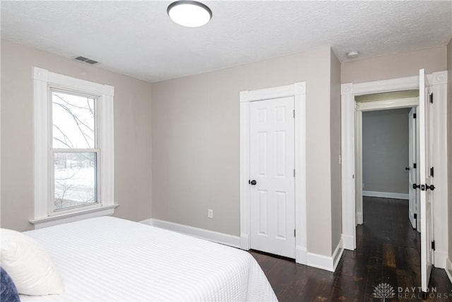 bedroom featuring a textured ceiling and dark hardwood / wood-style floors