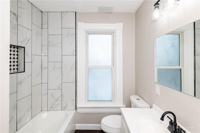 full bathroom with toilet, vanity, a textured ceiling, and tiled shower / bath