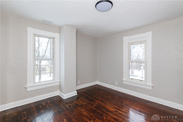 empty room featuring a textured ceiling and dark hardwood / wood-style flooring