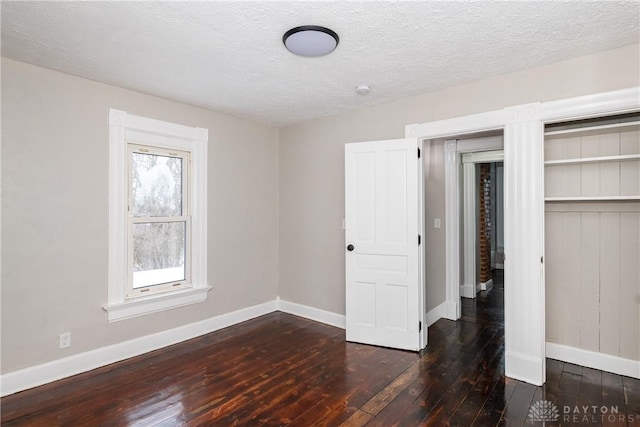 unfurnished bedroom with a textured ceiling, a closet, and dark hardwood / wood-style floors