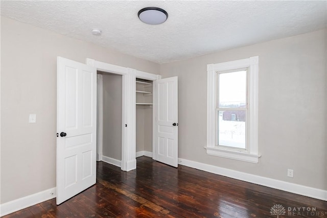 unfurnished bedroom featuring a textured ceiling, dark hardwood / wood-style floors, and a closet