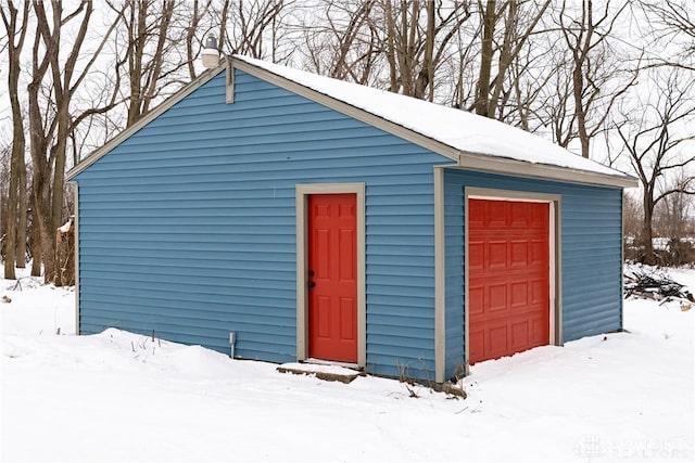 snow covered structure featuring a garage