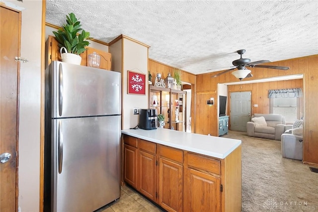 kitchen featuring wood walls, kitchen peninsula, stainless steel fridge, ceiling fan, and ornamental molding