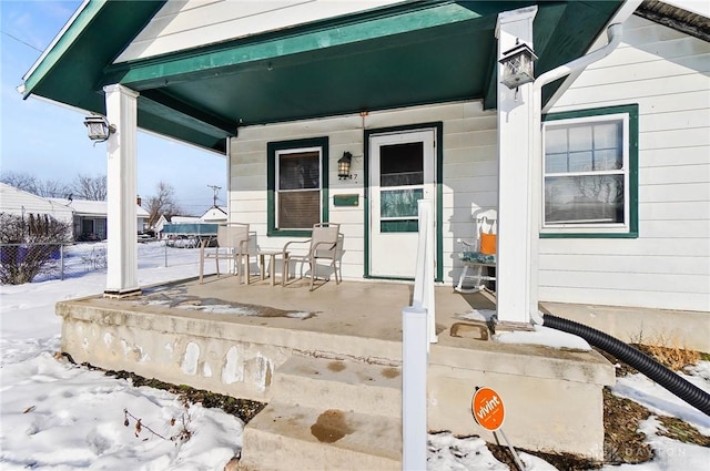 snow covered property entrance featuring a porch