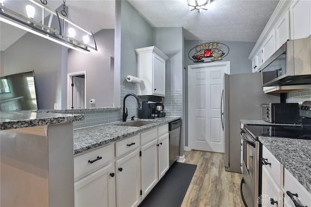 kitchen with sink, stainless steel appliances, light stone counters, light hardwood / wood-style floors, and white cabinets