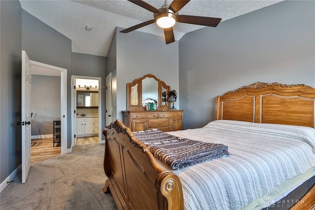 carpeted bedroom featuring vaulted ceiling, ensuite bath, sink, ceiling fan, and a textured ceiling