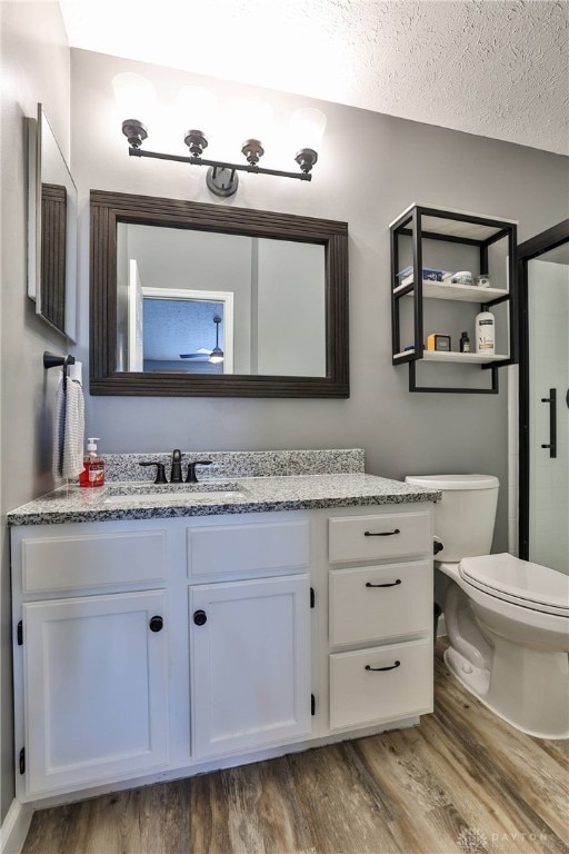 bathroom with wood-type flooring, vanity, a textured ceiling, and toilet