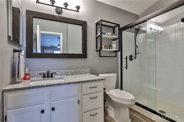 bathroom with hardwood / wood-style flooring, vanity, a textured ceiling, toilet, and walk in shower