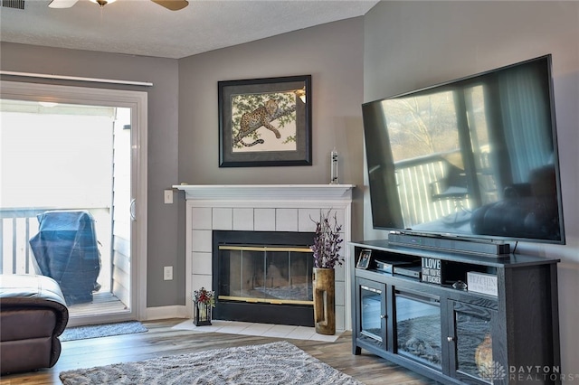 living room with a fireplace, vaulted ceiling, light hardwood / wood-style flooring, and a textured ceiling