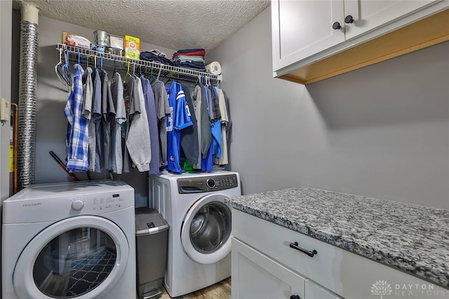 clothes washing area with cabinets, washer and dryer, and a textured ceiling