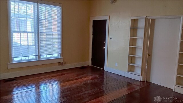 unfurnished bedroom featuring multiple windows and dark hardwood / wood-style floors