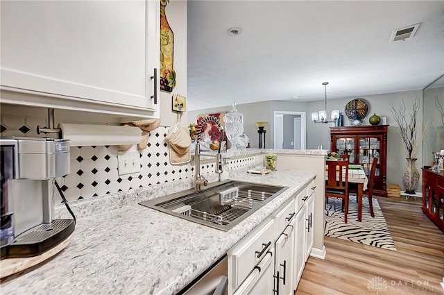 kitchen featuring light hardwood / wood-style floors, pendant lighting, a chandelier, and white cabinetry