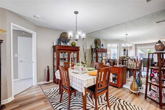 dining room with light hardwood / wood-style floors and a notable chandelier