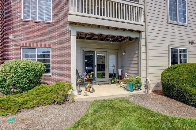 view of exterior entry featuring a patio area and a balcony