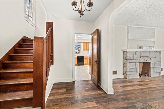 interior space with a fireplace, an inviting chandelier, a textured ceiling, and hardwood / wood-style floors