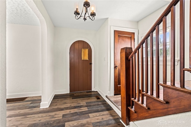 foyer with dark wood-type flooring, a textured ceiling, and a notable chandelier