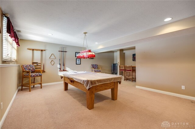 recreation room featuring a textured ceiling, pool table, and light carpet