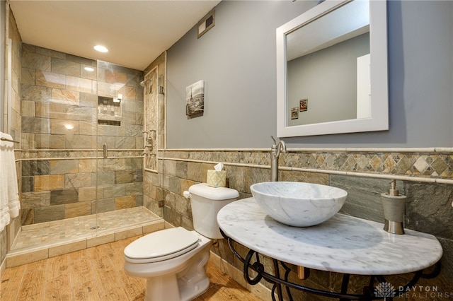 bathroom featuring sink, tile walls, toilet, and a tile shower