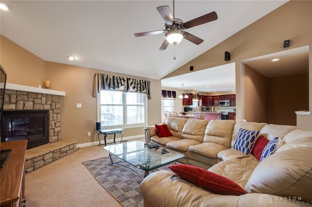 carpeted living room with ceiling fan, vaulted ceiling, and a fireplace