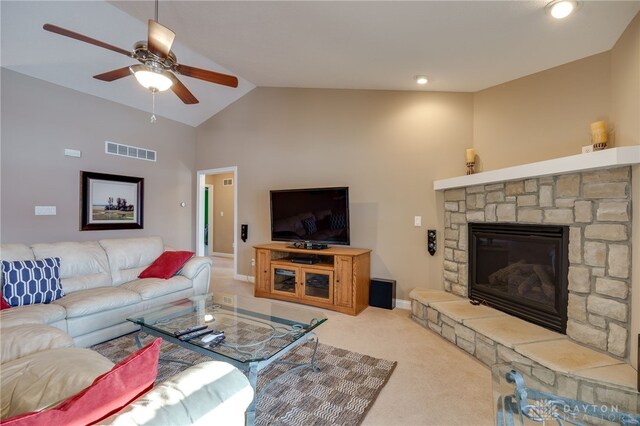 living room featuring ceiling fan, light carpet, a stone fireplace, and vaulted ceiling