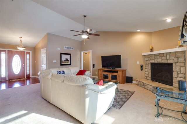 living room with lofted ceiling, ceiling fan, carpet, and a stone fireplace