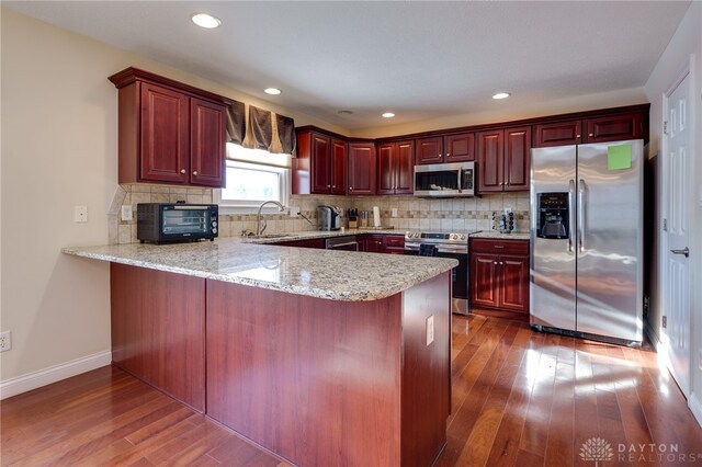 kitchen with stainless steel appliances, backsplash, and kitchen peninsula