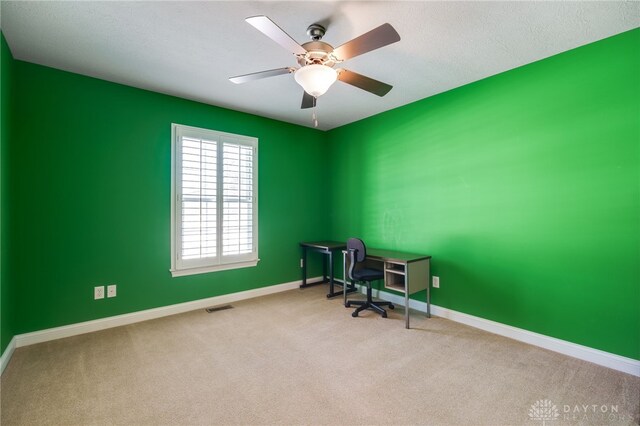 home office featuring ceiling fan, a textured ceiling, and light carpet